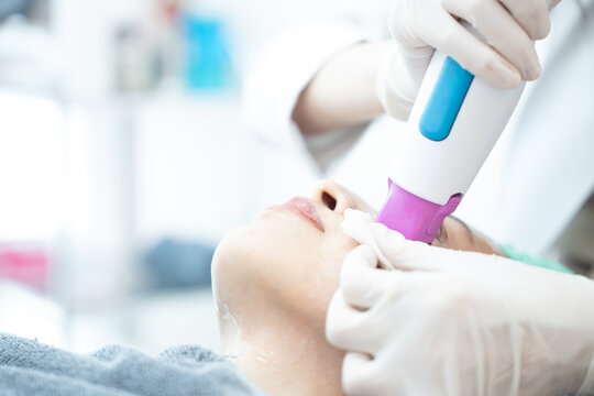 Beautician doing laser rejuvenation on woman face. Facial skin care.
