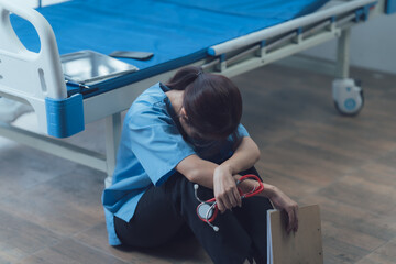 The Weight of Responsibility: A healthcare professional, overcome with exhaustion, sits slumped on...