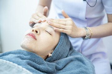 Naklejka premium Woman getting face massage in spa Salon, Female lying relaxed with eyes closed.