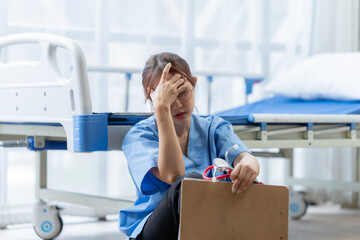 Exhausted Nurse: A young nurse, exhausted and overwhelmed, sits slumped on the floor of an empty...