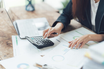 Businesswoman Calculating Financial Data: A close-up image of a businesswoman's hands working on a calculator, surrounded by financial documents and a laptop.