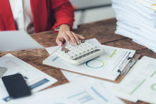 Financial Planning:  A woman's hands meticulously operate a vintage calculator amidst a sea of financial documents and reports on a rustic wooden desk.  The image evokes a sense of focus, precision.
