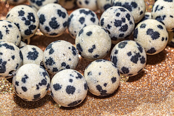 Beautiful round beads of spotted Dalmatian jasper in macro photography, perfect for crafting and jewelry design. Decorative round stone beads of white colors with black spots for boho jewelry design.