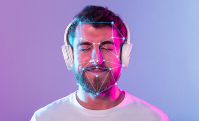 A young man with a beard listens to music while wearing headphones, enjoying a moment of relaxation. Colorful lights enhance the ambiance around him, showcasing facial recognition patterns.