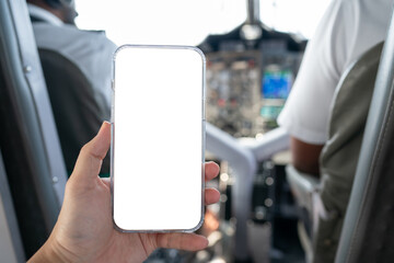 Hand with white blank mobile phone screen mockup with airplane cockpit background.