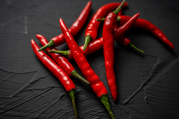 A pile of red, hot chili peppers on a black background. View from above. Close-up.