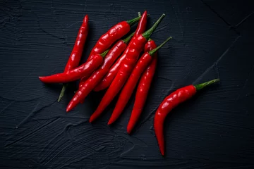 Fotobehang Chili Pepers A pile of red, hot chili peppers on a black background. View from above. Space for text Close-up.  © Andy Shell