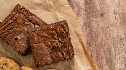 Close-up of chocolate brownies on parchment paper over wooden surface, perfect for dessert or snack concepts.
