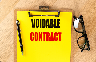 Clipboard with voidable contract text, black pen, and glasses on a wooden desk