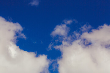 Obraz premium Cumulus clouds. Beautiful dark blue dramatic sky. Copy space for lettering. Few clouds against a blue sky on a sunny day.