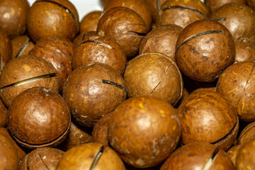 Close up of ripe macadamia nuts in their shells. Photograph showcases the natural texture of the nuts, perfect for culinary, health, and food-related projects. 