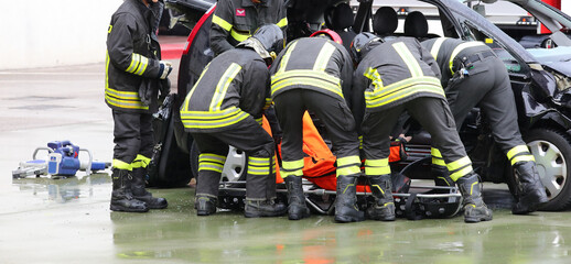firefighters assisting the injured person with a stretcher after a car crash with a destroyed...