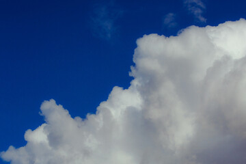 Cumulus clouds. Beautiful dark blue dramatic sky. Copy space for lettering. Few clouds against a blue sky on a sunny day.