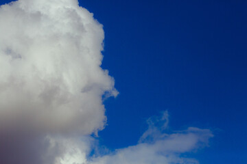 Cumulus clouds. Beautiful dark blue dramatic sky. Copy space for lettering. Few clouds against a blue sky on a sunny day.