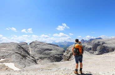 Fototapeta premium hiker with a backpack on shoulders admiring the view of the dolomites in the european alps in northern italy