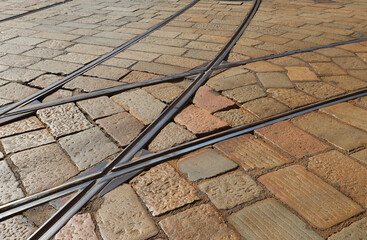 interwoven tram tracks on historic stone block pavement in a metropolitan setting