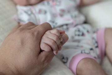 New born girl hand holding father hand during baby sleeping. newborn baby and dad hands. father taking care of his daughter happy family dream of health