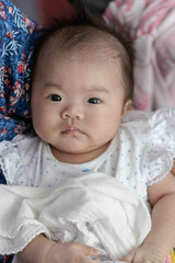 Happy Smiling face Asian Chinese baby girl during lying on bed. Happy Newborn child relaxing in bed