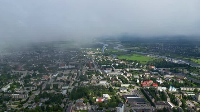 cityscape of Jelgava, Latvia with the Lielupe River winding through green fields and fog over the ctiy