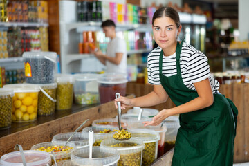 Female supermarket grocery seller offers to buy pickled green olives