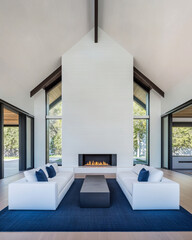 Modern living room with large windows and a minimalist fireplace in a serene outdoor setting