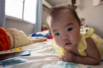 Happy Smiling face Asian Chinese baby girl during lying on bed. Happy Newborn child relaxing in bed