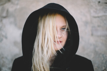 Blonde Woman in Hooded Coat Against Textured Wall