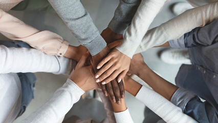 Close up of international business team showing unity with putting their hands together on top of each other. Concept of teamwork, top view