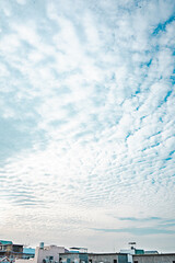 Expansive Sky with Patterned Clouds over Urban Rooftops in Soft Morning Light