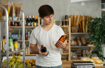 European man chooses whiskey in a grocery store. Buyer looks with interest at a bottle of strong...