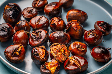 Roasted chestnuts on a blue plate. Close-up. View from above.