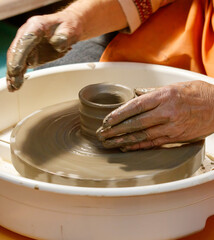 A person is making a pottery piece in a white bowl