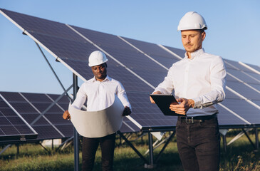 Engineers Inspecting Solar Panels on Sunny Day at Solar Farm