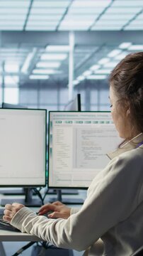 Smiling manager in server hub using computer to find firewall misconfigurations affecting rackmounts performance. Upbeat supervisor checking systems bottlenecks affecting data transfer rates, camera B