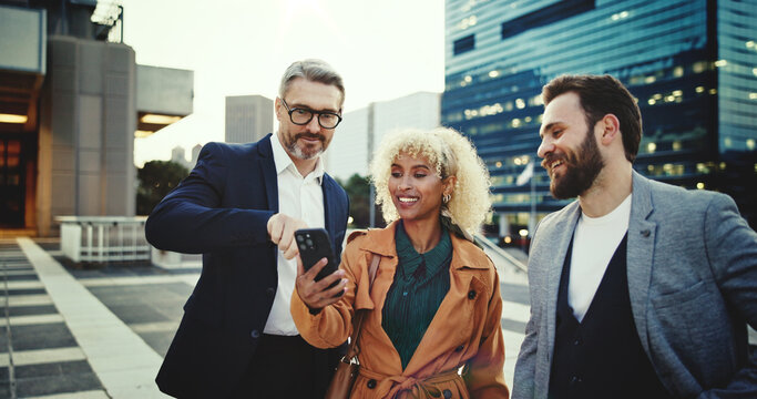 App launch, city and friends with phone, together for communication, networking or social media. Business, funny or meme with colleague man and woman group outdoor in urban town for humor or joking - Powered by Adobe