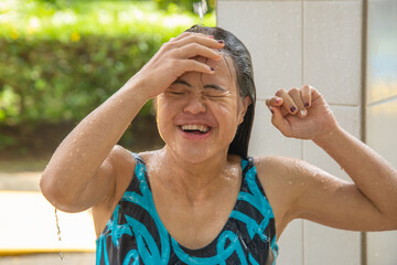 Girl with Down syndrome taking a shower before entering the pool on a summer day. inclusion,...