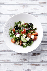 Healthy Salad with Feta Cheese, Black Olives, Cucumber and Cherry Tomatoes. Bright background. Top view. 