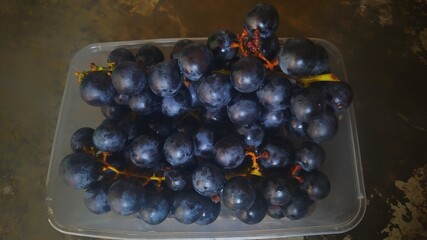Ripe red grapes in a container on a dark background