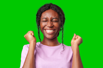 Joyful woman celebrating success with clenched fists against a bright green background