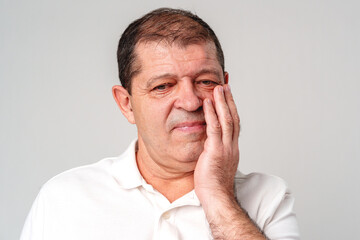 Obraz premium Concerned older man touching his face in a neutral-toned setting reflecting an emotional moment