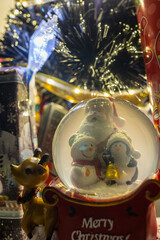 Christmas snow globe with santa claus, snowman, and penguin figurines surrounded by christmas...