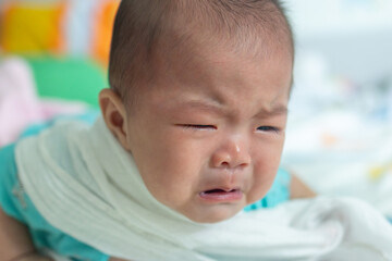 Newborn baby crying while lying on bed