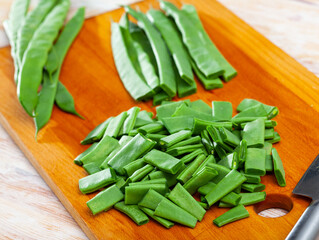 Image of cut fresh green beans on wooden surface in home kitchen