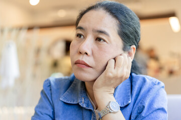 Young woman who feels exhausted and Unhappy sitting on the sofa at the coffee shop, looking to the side, feeling stressed and irritated. Bored and tired of Negative concepts.