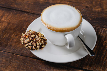 Cappuccino coffee in white porcelain cup on wooden table