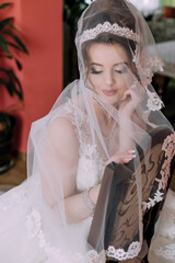 A woman in a white dress is sitting on a chair with a veil covering her face. Concept of mystery...