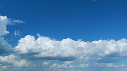 Clouds running across the blue sky. White puffy and fluffy clouds on blue sky. Time lapse.