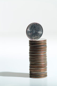 High angle close up of a stack of US quarters, silver coloured coins with one on end