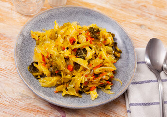 Traditional stewed white cabbage with vegetables served on plate. Delicious vegetarian food.