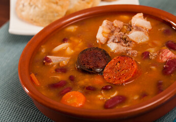 Delicious Fabada asturiana with stewed beans, pork, morcilla and chorizo served in traditional clay...